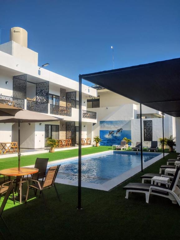 a building with a pool and a table and chairs at Houzze Plety in Brisas de Zicatela