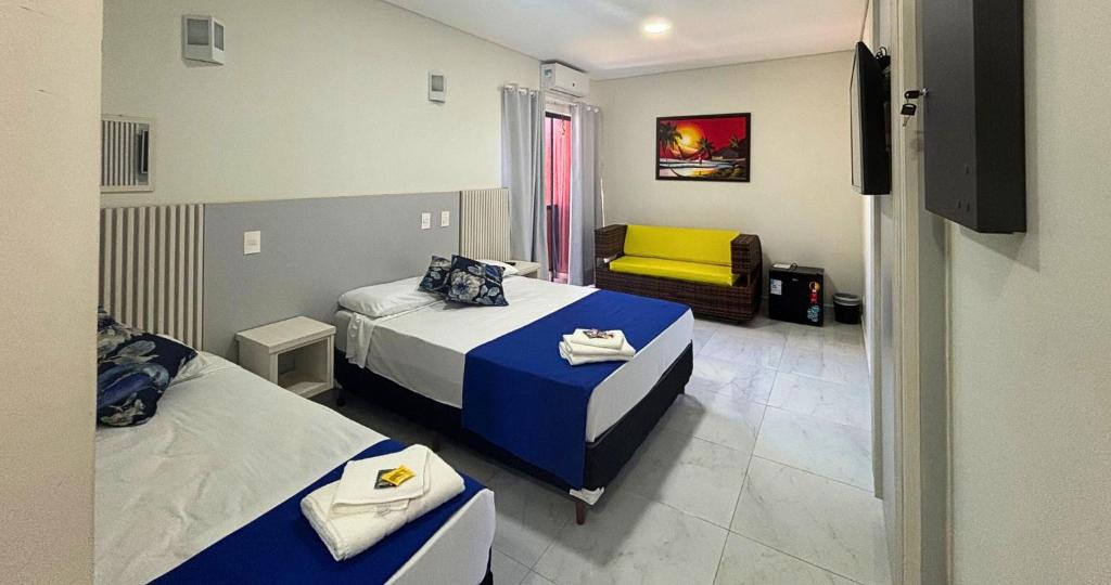 a hotel room with two beds and a chair at Hotel Amaromar in Pontal do Paraná