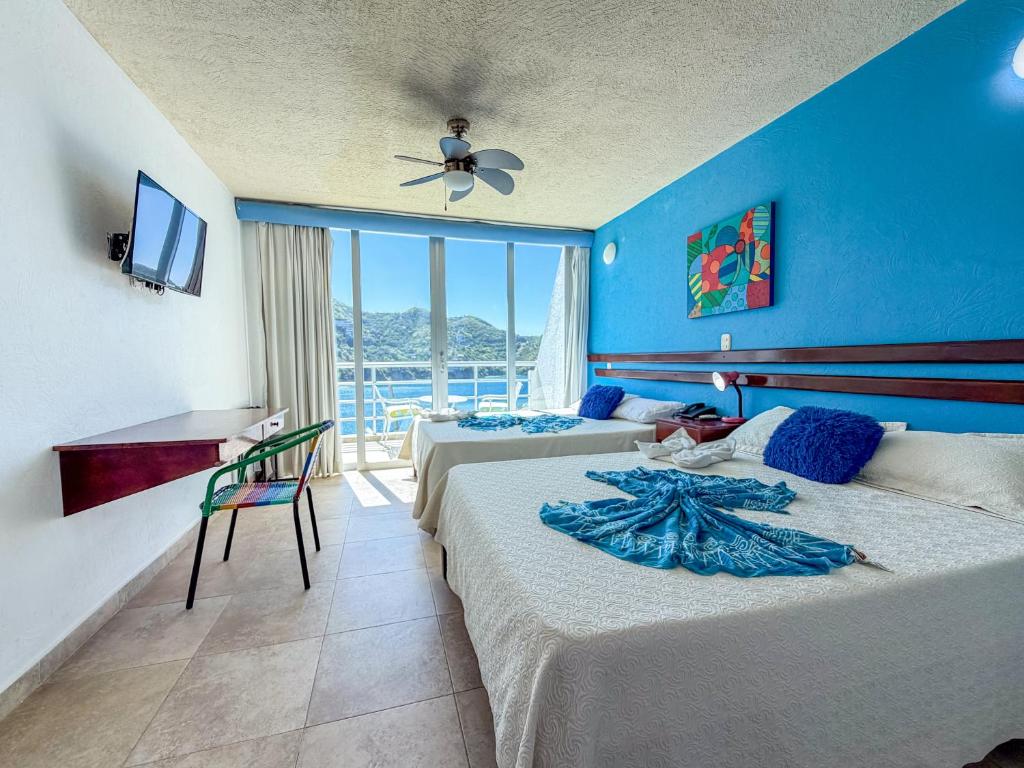 een slaapkamer met 2 bedden en een blauwe muur bij Hotel Bahia Taganga in Taganga