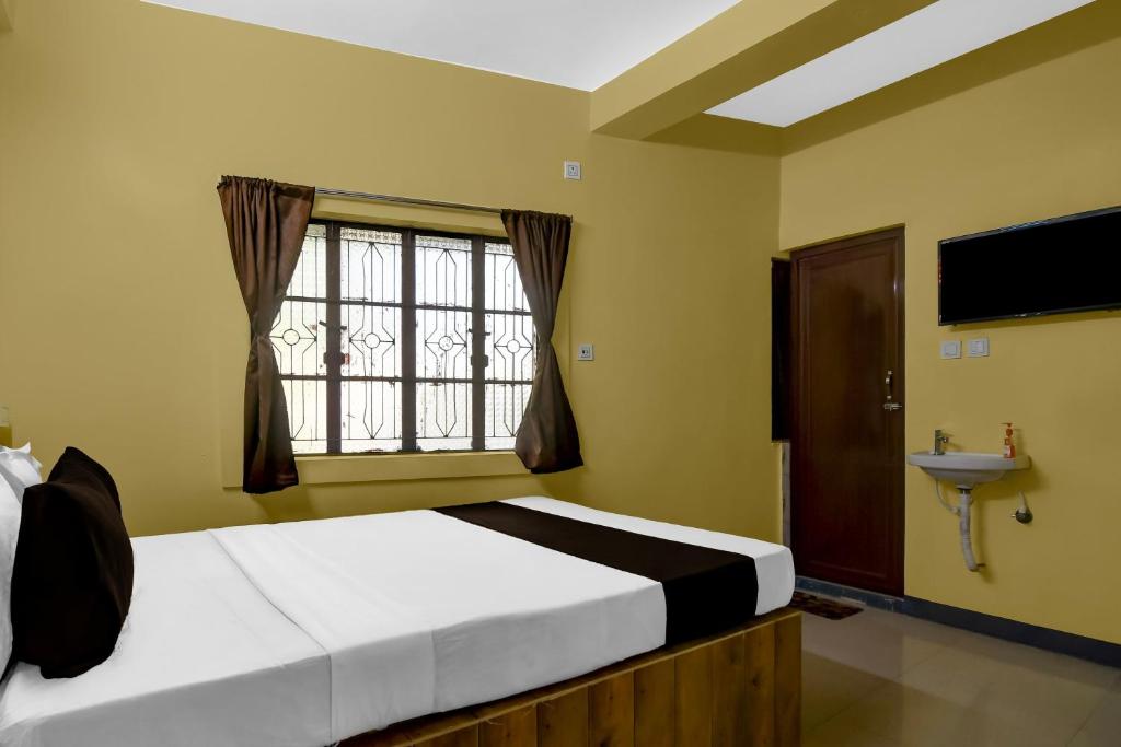 a bedroom with a bed and a window and a sink at POP 84107A Hotel O J J Lodge in Āsansol