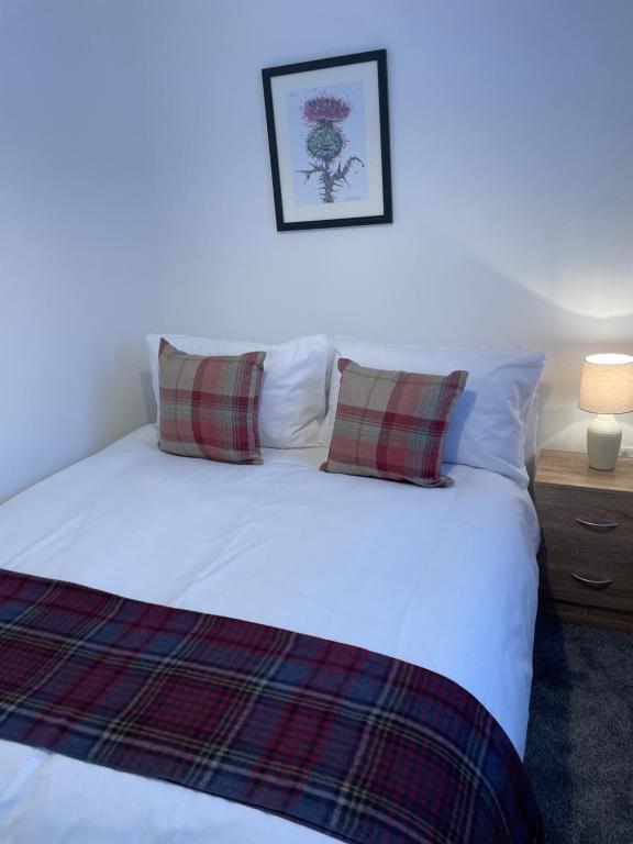 Garden Room at Tartan House في إينفيرنيس: غرفة نوم بسرير ابيض مع وسادتين