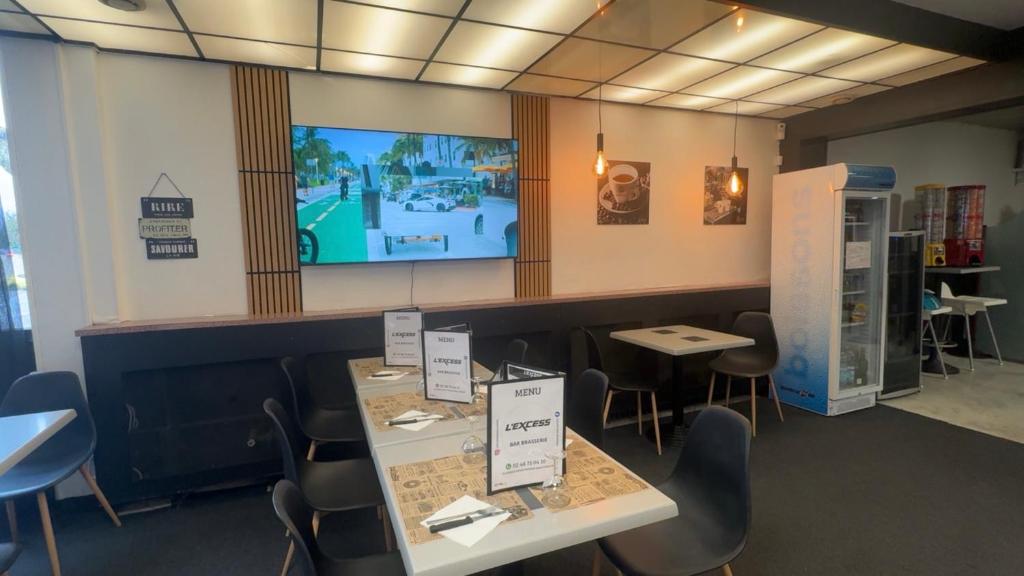 a restaurant with tables and chairs and a tv on the wall at GOOD NIGHT HÔTEL By L'excess in Vierzon