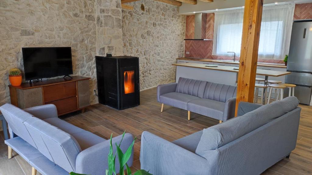 un soggiorno con 2 divani e una stufa a legna di La Cantizada a Viloria