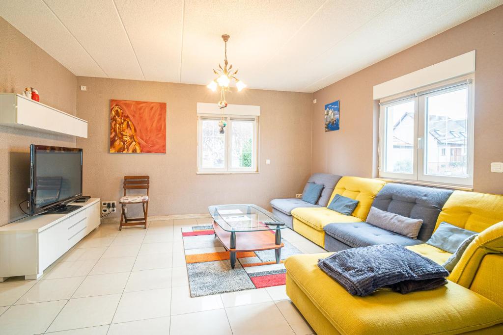 a living room with a yellow couch and a tv at Ma Vie'La - Swimming Pool - Balneo - Jacuzzi - Sauna in Rhinau