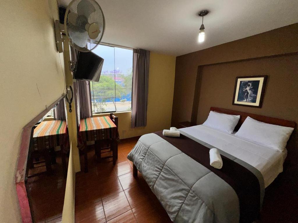 a bedroom with a bed with a fan and a window at La Posada del Rey - Lima Airport Hostel in Lima