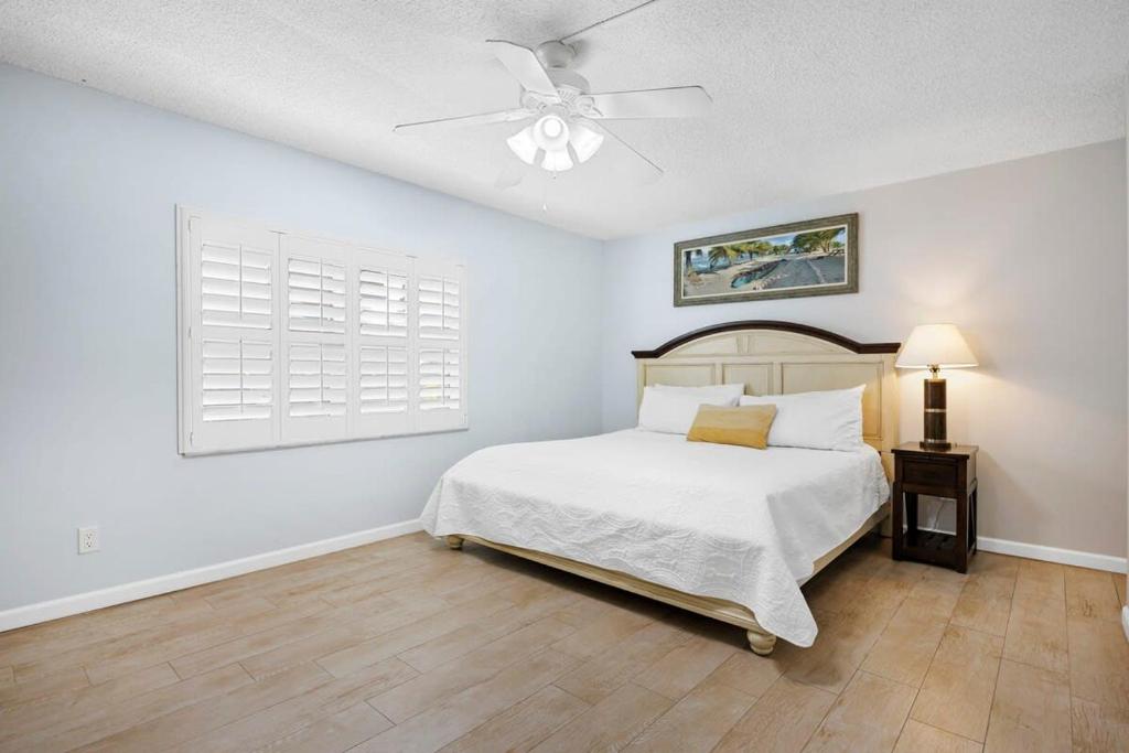 een witte slaapkamer met een bed en een plafondventilator bij Cocoa Beach Club-Beachfront Condo in Cape Canaveral