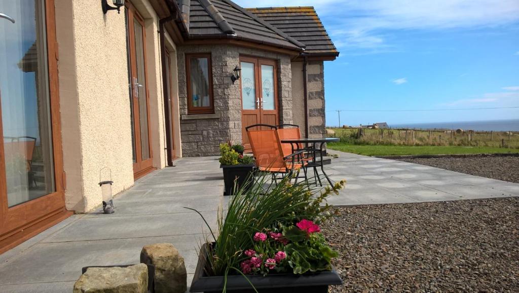a porch of a house with two chairs and flowers at A Castle View in Keiss