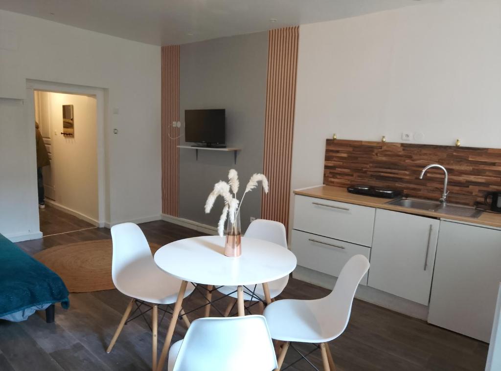 a kitchen with a white table and white chairs at Le Petit Logis Noblat 1 in Saint-Léonard-de-Noblat