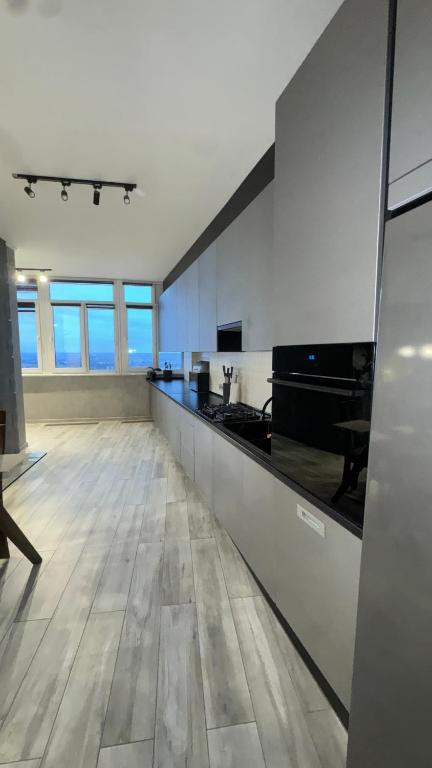 a large kitchen with white walls and a wooden floor at Люкс студия в центре города in Zarechʼye