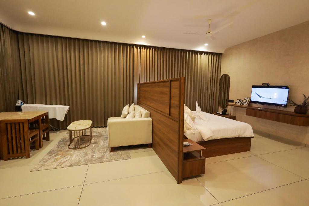 a hotel room with a bed and a desk and a television at Town Square Residency in Kommeri