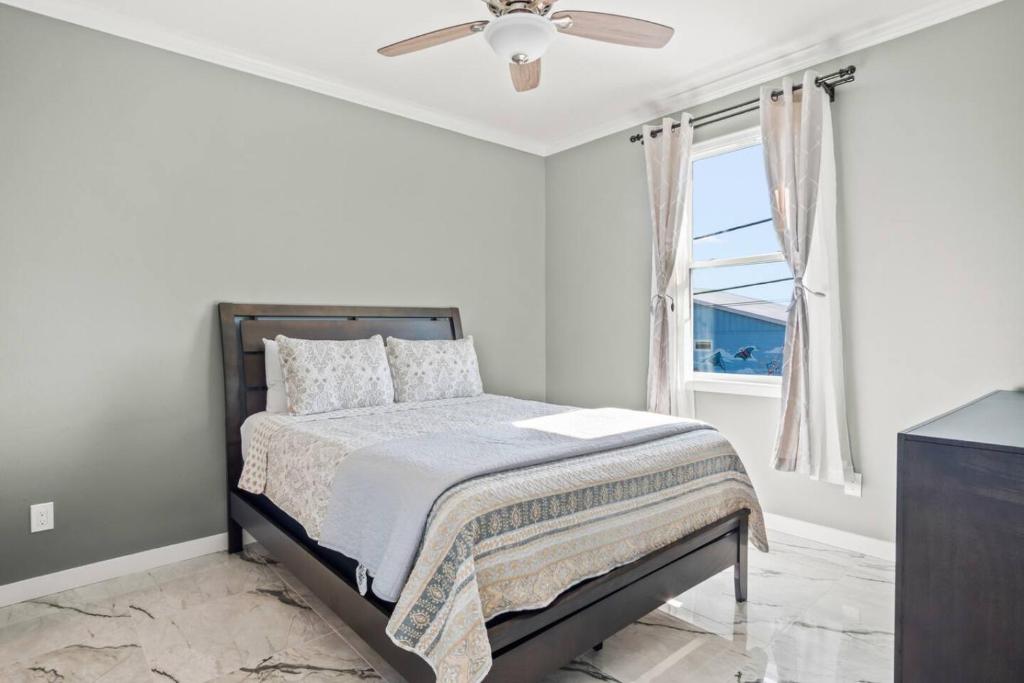 Casa San Juan Jr. في ميناء أرانساس: غرفة نوم بيضاء مع سرير مع مروحة سقف