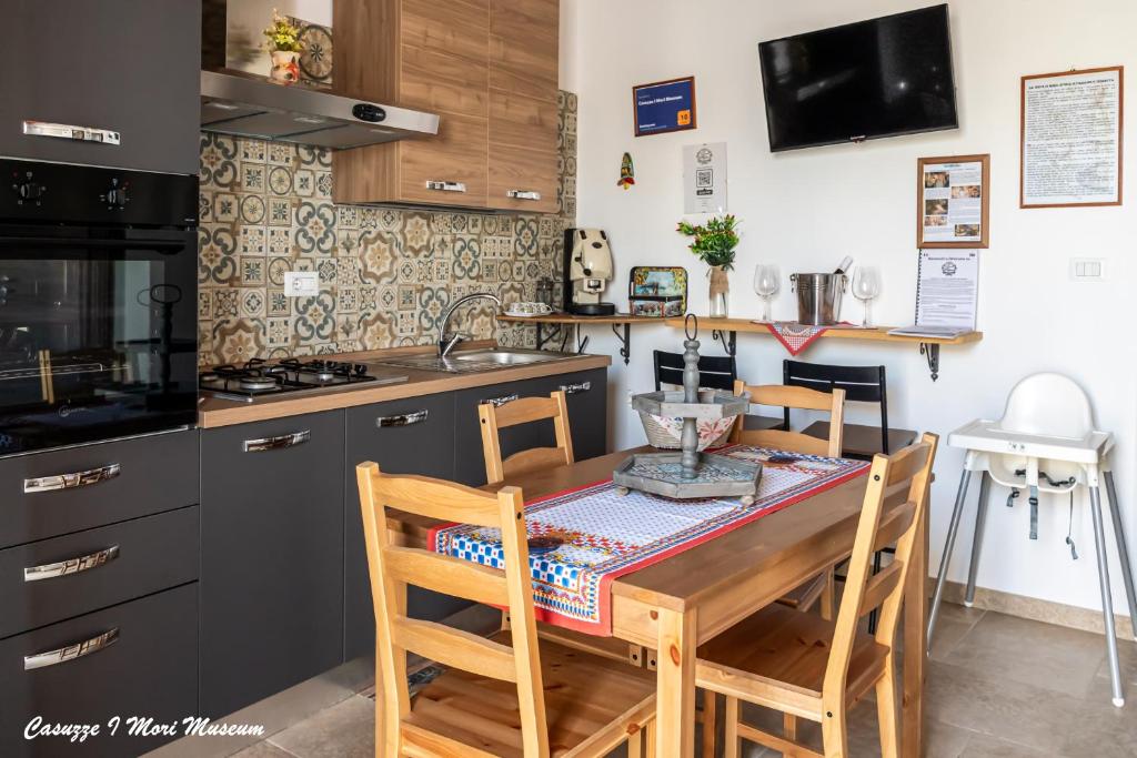 eine Küche mit einem Tisch mit Stühlen und einem Waschbecken in der Unterkunft Casuzze I Mori Museum Alloggi di Charme tra Mare Natura e Tradizione Siciliana in Marzamemi