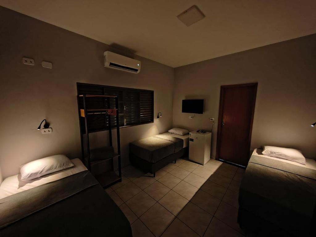 a hotel room with two beds and a refrigerator at Hotel Pousada Narandiba in Narandiba