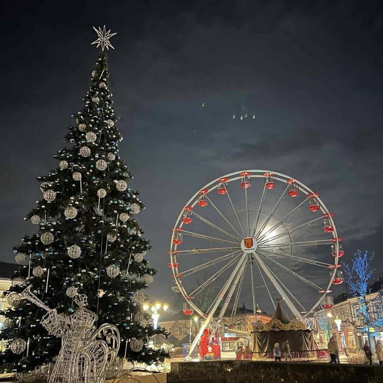 a christmas tree and a ferris wheel at night at Hotels Widok Rynek Centrum-fvat in Kielce