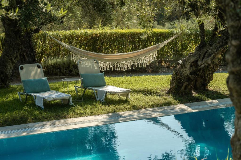 two chairs and a hammock next to a swimming pool at 3 Sorelle Private Stone Villa in Lithakia