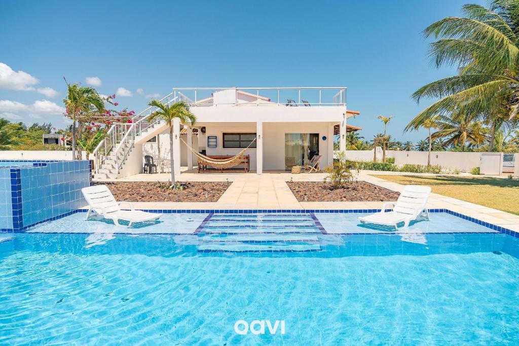 a swimming pool with two chairs and a house at Casa Palm Paradise em Touros by Qavi in Touros