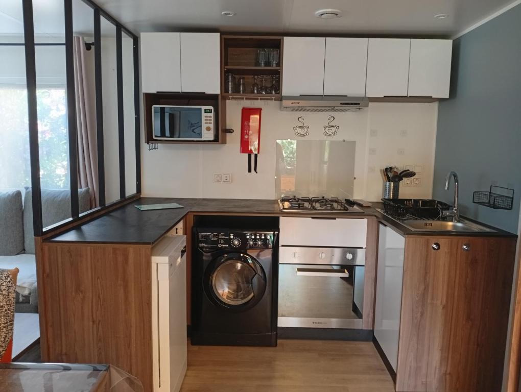 eine Küche mit Waschmaschine, Herd und Geschirrspüler in der Unterkunft Spacieux mobil home 40 m2 tt conf 5 p in Fréjus