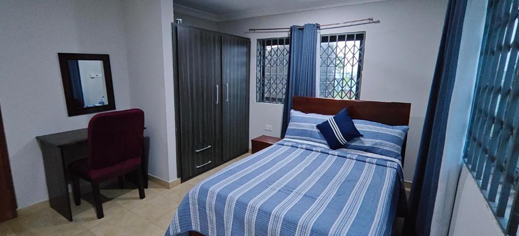 a bedroom with a bed and a chair and a desk at Purple Springs Elmina #3 in Esamang