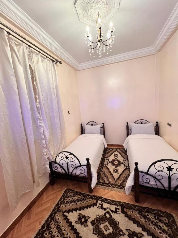 two beds in a room with a chandelier at Tumsilt in Marrakesh