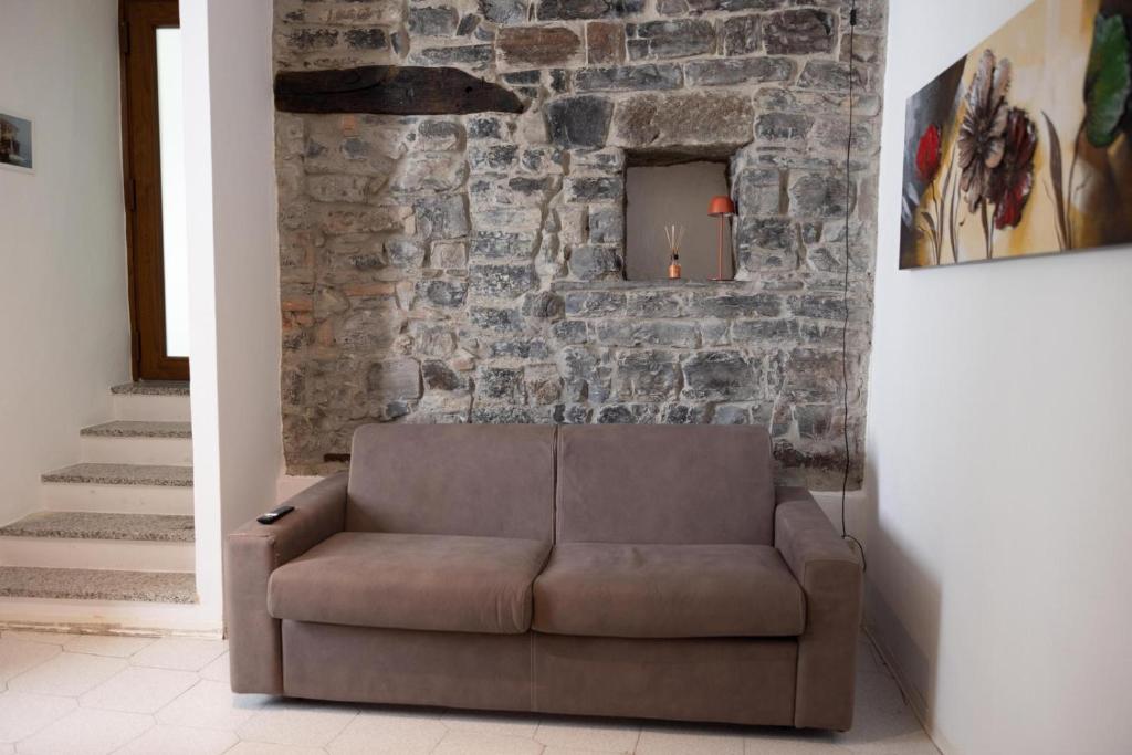 La Piccola Corte nel cuore di Como AC e wifi في كومو: أريكة بنية في غرفة بجدار حجري