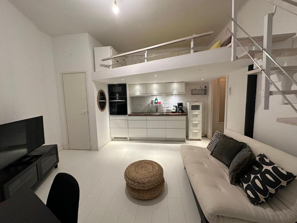 a living room with a couch and a kitchen at Bright Loft Apartment Steps From Linnanmäki & Alppipuisto in Helsinki