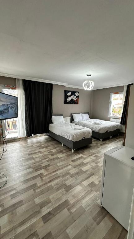 two beds in a large room with wooden floors at Gürleyen Butik Otel in Küçük Çığlı