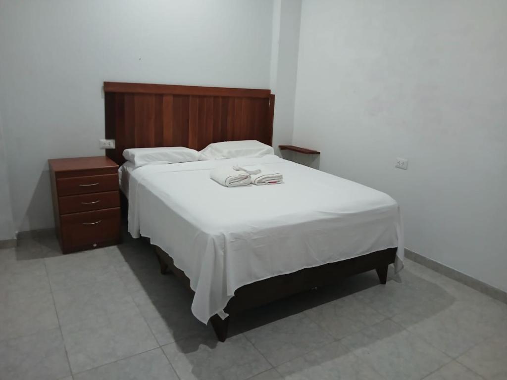 Un dormitorio con una gran cama blanca con cabecero de madera. en Amaru Lodge, en Tingo María