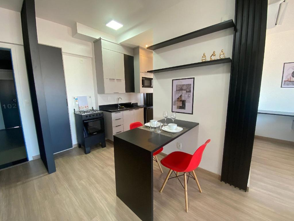 a kitchen with a black counter and red chairs at Apt completo: ar cond piscina e academia no Centro in Taubaté
