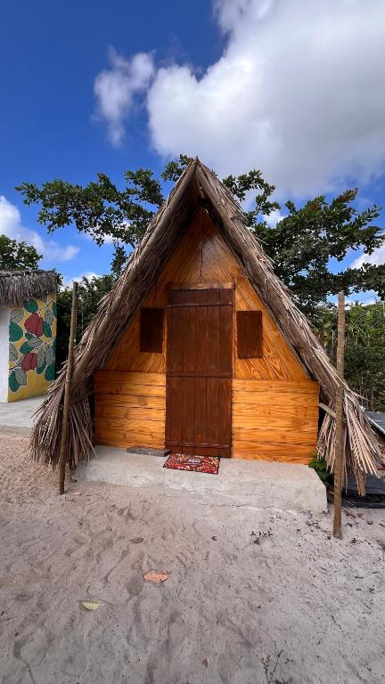 a small wooden hut with a thatched roof at Camping Proibido Não Viver in Cruz