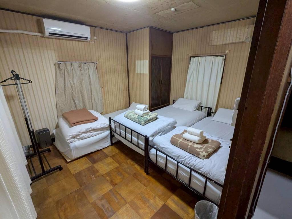 een slaapkamer met twee bedden en een stoel erin bij Hikari Kitaayase - 光莉 北綾瀬 - 浅草や上野へアクセス良好 MAX11名の和風宿 無料Wi-Fi in Tokyo