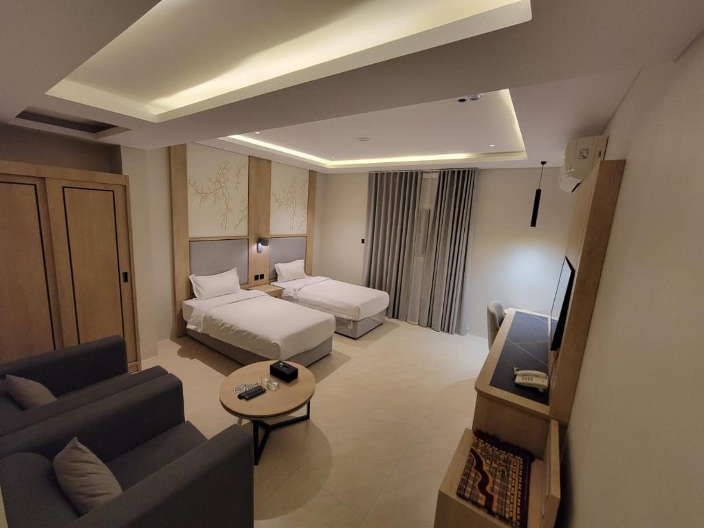 a hotel room with a bed and a couch and a tv at افاق بلس للشقق المخدومه in Hafr Al Baten