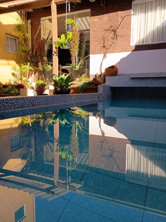 a swimming pool with plants and a reflection in the water at Pousada Casa Jardim in Serra Negra