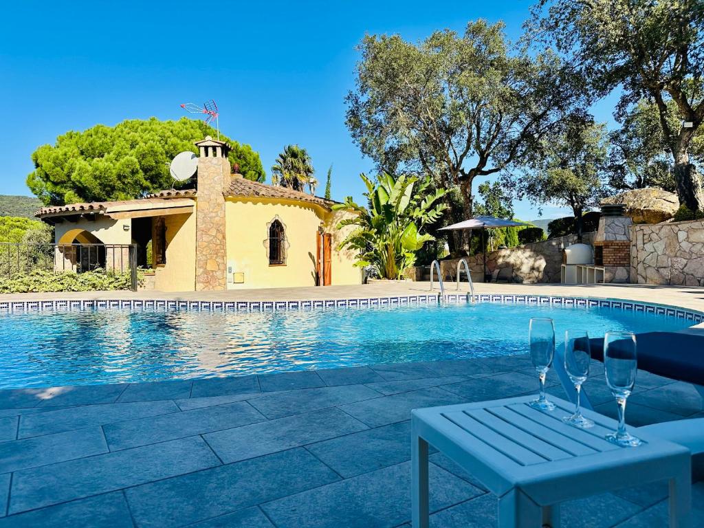 een villa met zwembad met twee wijnglazen op een tafel bij Paliane CostaBravaSi in Calonge