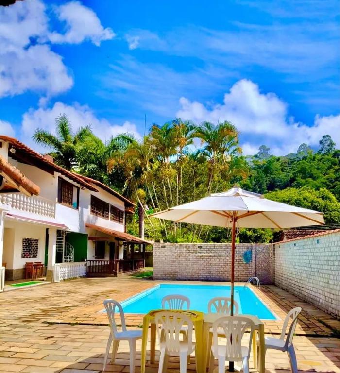 a table with an umbrella next to a swimming pool at Espaço 579 in Miguel Pereira