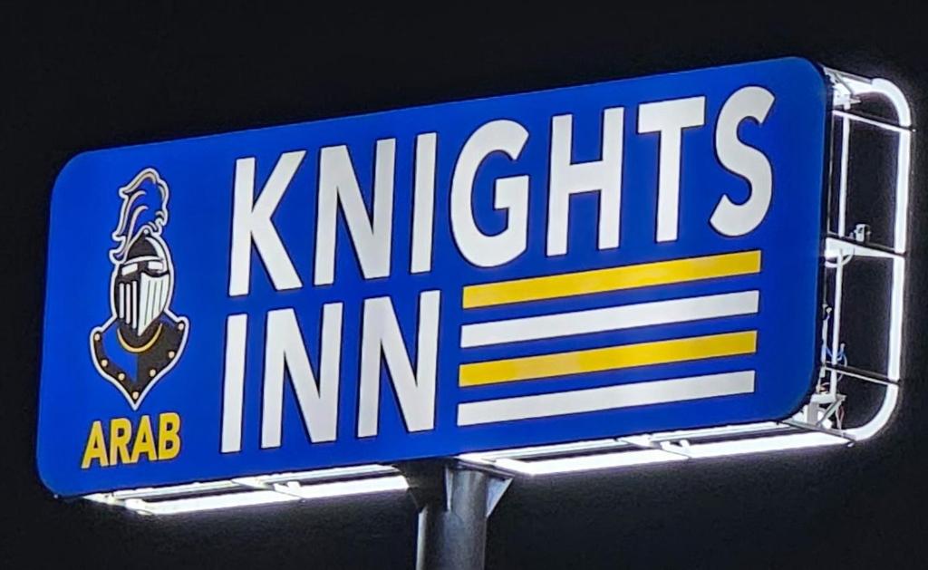a blue and white street sign with the nittis inn at ArabKnightsInn in Arab