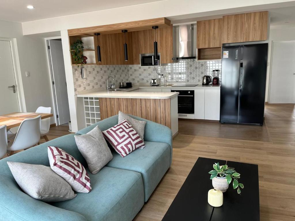 Moderno dpto de estreno en zona centrica في أريكيبا: غرفة معيشة مع أريكة زرقاء ومطبخ