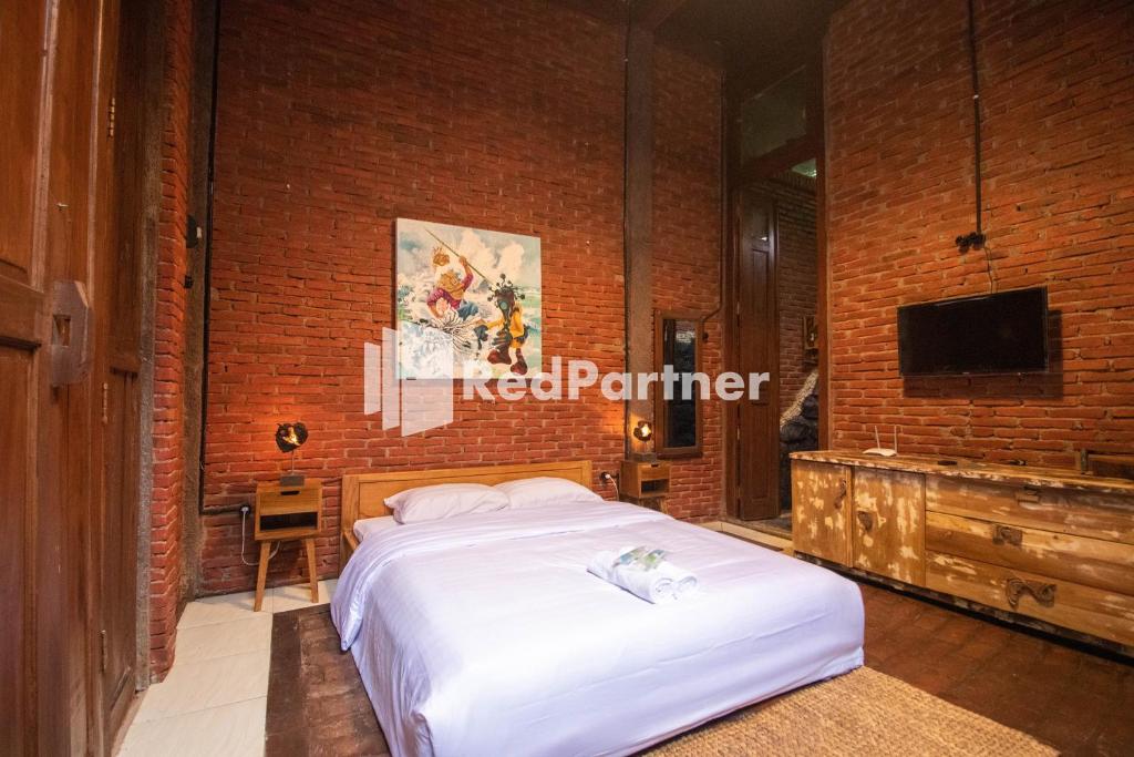 a bedroom with a bed and a brick wall at Djawata Resort & Gallery near Desa Wisata Kasongan Yogyakarta RedPartner in Yogyakarta