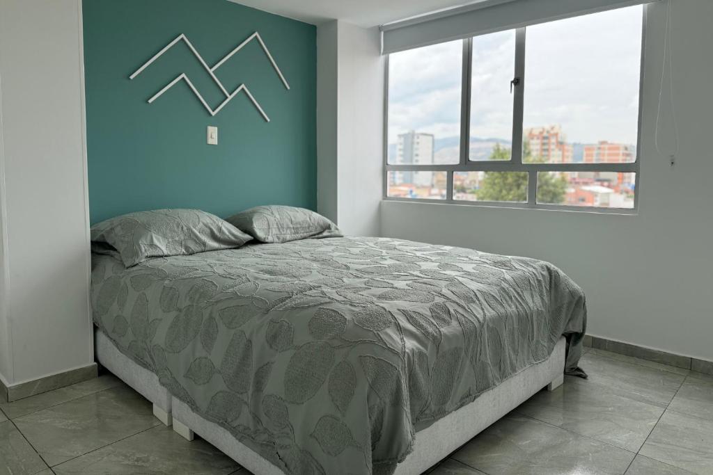 a bedroom with a bed with a blue wall at Increíble Apartamento En Sogamoso in Sogamoso
