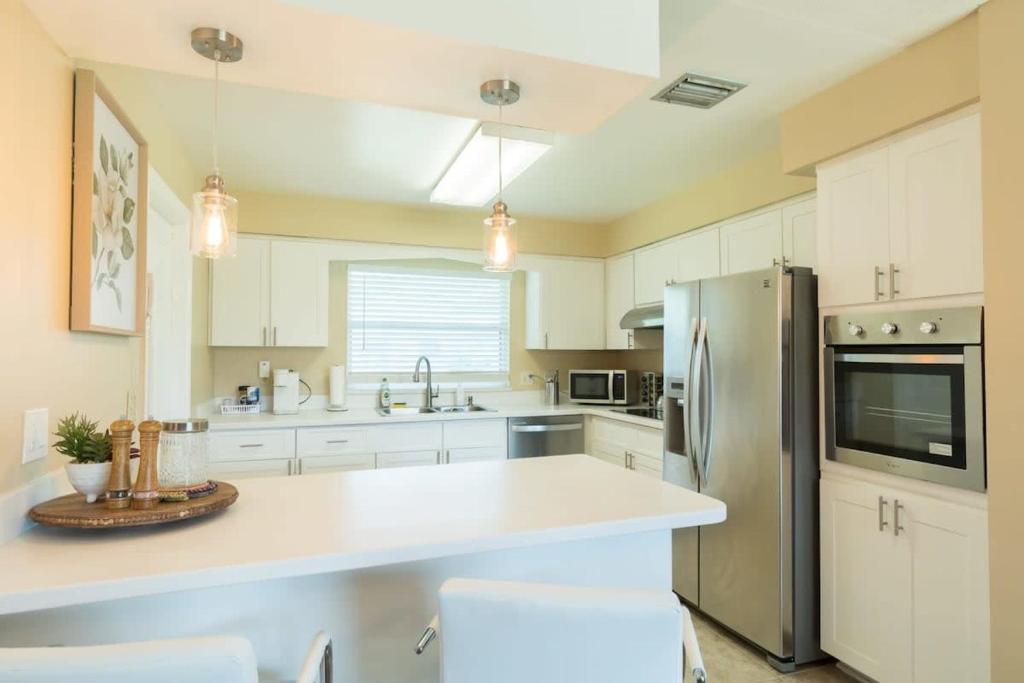 eine Küche mit weißen Schränken und einem Edelstahlkühlschrank in der Unterkunft Spacious 4 Bedroom Home near USSSA Complex in Rockledge