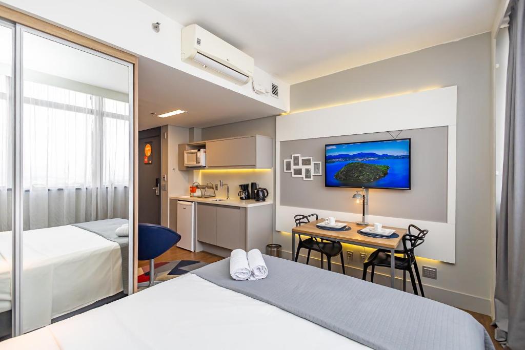 a hotel room with two beds and a table and a kitchen at Helbor Stay Batel in Curitiba