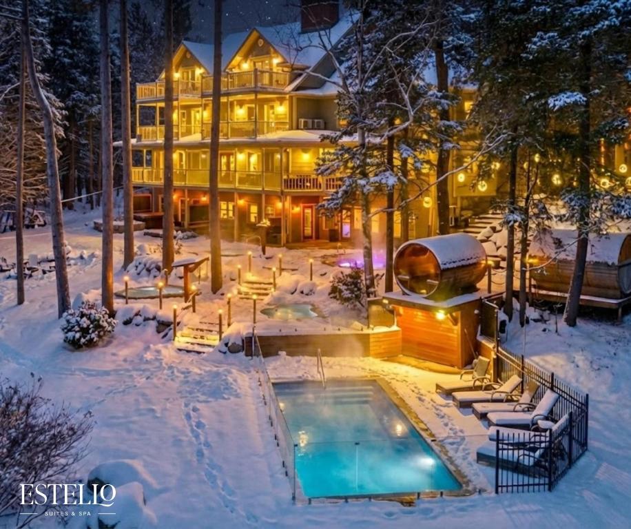 a house in the snow with a swimming pool at Estello Suites & Spa in Lac-Mégantic