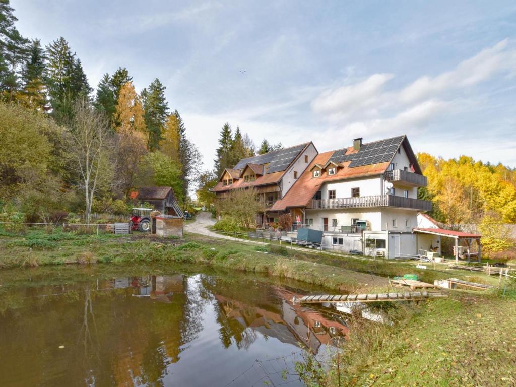 a large house next to a river with trees at Weiherblasch II in Schönsee