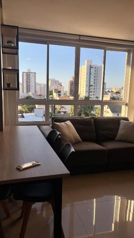 a living room with a couch and a table at Loft Completo Com Piscina, no centro in Tubarão