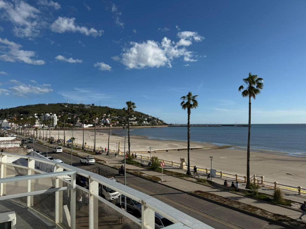 Blick auf einen Strand mit Palmen und das Meer in der Unterkunft Hotel Atlantico in Piriápolis