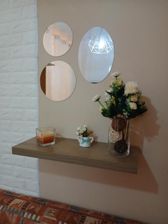a shelf with three mirrors and a candle and flowers at Kannon 1 5-minute walk to all transport options at the Pragal terminal in Caparica