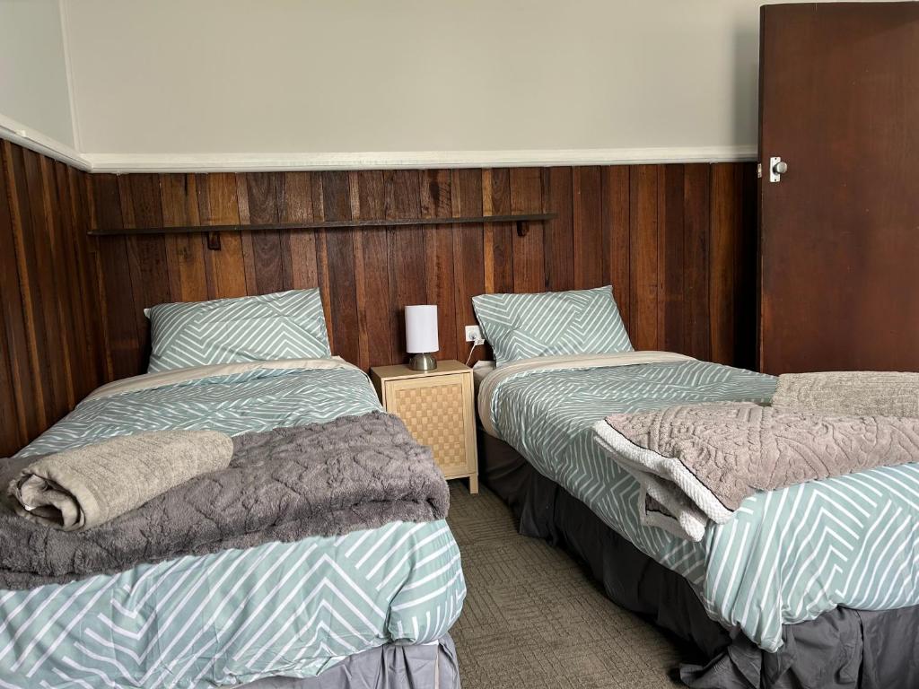 two beds in a room with wooden walls at Bemm River Bungalows - Bellbird Abode - Bungalow 1 in Bemm River