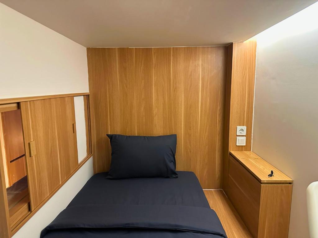 a small room with a bed and wooden walls at Althia Capsule Quarters in Badung