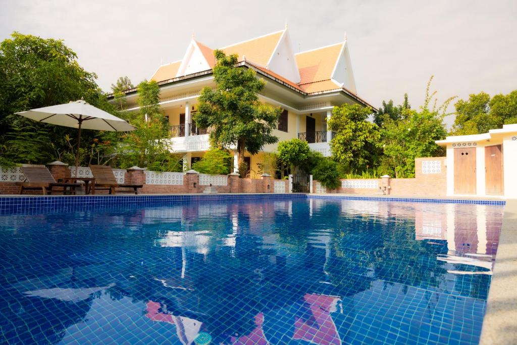 a swimming pool in front of a house at La maison bleue BTB in Phumĭ Kâmpóng Âmpĭl