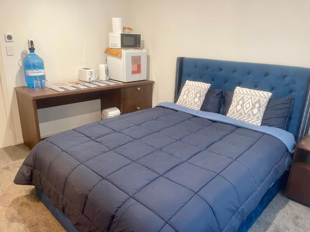 Un dormitorio con una cama azul y un escritorio. en Modern Ensuite Room with Light Kitchenette & Private Entrance in Cromwell, en Cromwell