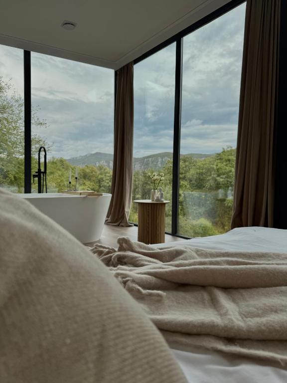 a bedroom with a tub and a large window at Nest House in Dubova